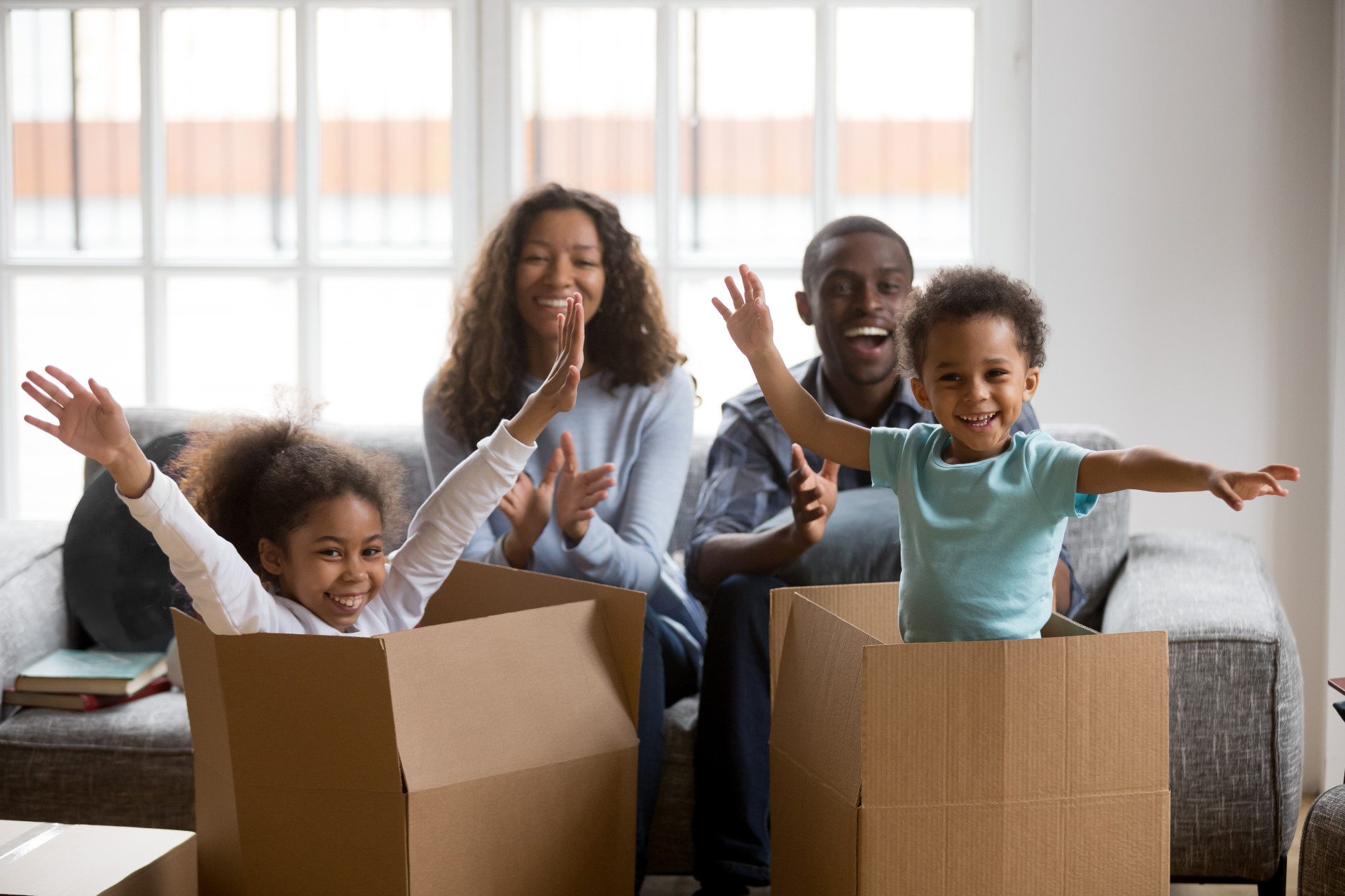 Happy young family with cardboard boxes in new home at moving day.